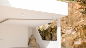 A modern interior with a large rock wall and a sloped ceiling. - Yamu Hills Panoramic Ocean View 6 Bed Luxury Vila (Pa Klok)