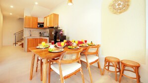 A modern kitchen with wooden cabinets, a dining area with a wooden table and chairs, and a small island with a sink. - The Canggu Dome 2-Roof Top Villa (Canggu)
