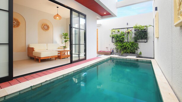 A modern indoor pool area with a glass-enclosed seating area, a pool, and potted plants. - The Canggu Dome 2-Roof Top Villa (Canggu)