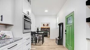 A modern kitchen with white cabinets, a dining area with a table and chairs, and a green door. - Entire home, in Goldsboro North Carolina (Goldsboro)
