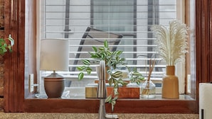 A kitchen with a double stainless steel sink, a potted plant, and a window with blinds.