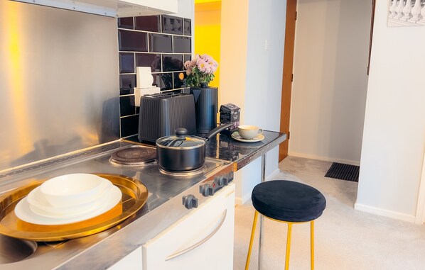 A modern kitchen with stainless steel appliances, a black and white backsplash, and a yellow accent wall.