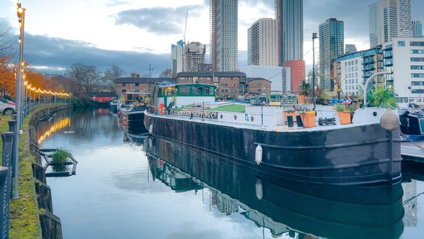A river with a boat docked, surrounded by tall buildings and a cloudy sky. - London - Apartment - Riverside - Sleeps 3 - Garden (London)