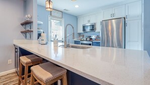 A modern kitchen with a large island, stainless steel appliances, and a view of the sea.