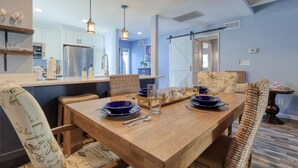 A dining area with a wooden table set for four, surrounded by wicker chairs.