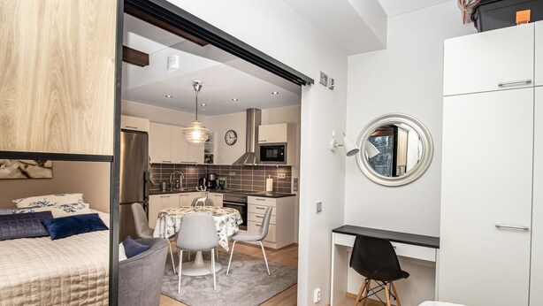 Eine kompakte, moderne Wohnung mit Küchenzeile, Essbereich und Schlafzimmer.