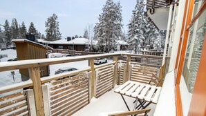 Ein mit Schnee bedeckter Balkon mit hölzernen Geländern und einem Tisch mit einer Bank.