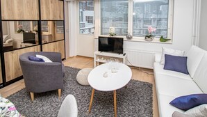 Ein modernes Wohnzimmer mit einem weißen Sofa, einem grauen Sessel und einem runden Couchtisch.