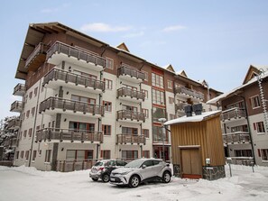 Ein mehrstöckiges Hotel mit Balkonen, einer Skiliftanlage und einem überdachten Bereich.