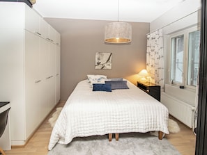 A bedroom with a bed, a nightstand, a lamp, a window with curtains, and a wardrobe. - Kelotähti a 11 by Interhome (Inari)