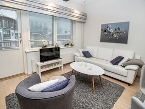 A modern living room with a sofa, a grey armchair, a coffee table, and a TV on a white stand. - Kelotähti a 11 by Interhome (Inari)