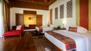 A hotel room with a wooden ceiling, a large bed with a patterned blanket, two smaller beds, a red sofa, and decorative wall panels. - Eden Pool Villa  (Rawai)