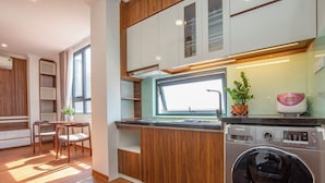 Une cuisine moderne dotée d’un lave-linge et d’un sèche-linge intégrés, de meubles de rangement en bois et d’un coin repas avec une table et des chaises.