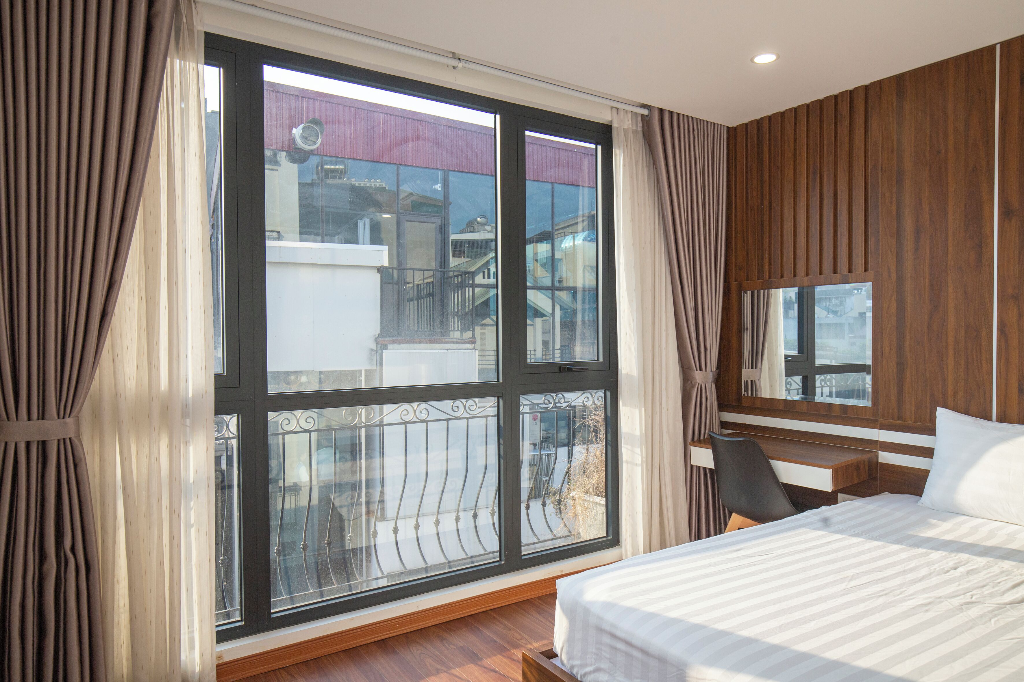 Une chambre d’hôtel avec une grande fenêtre, un lit, un bureau et une chaise.