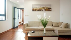 Un salon moderne avec un canapé beige, une table basse en verre et un tableau accroché au mur.