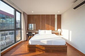 Quarto moderno com uma cama grande, painéis de madeira, uma escrivaninha e vista pela janela ampla.