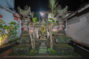 Un templo con una estatua central, rodeado de escalones de piedra y vegetación.