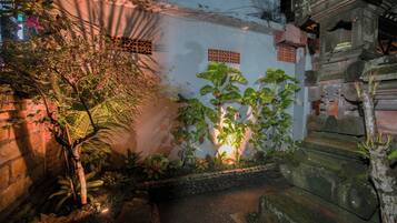 Un estrecho callejón con un muro de piedra, un árbol pequeño y una planta en maceta.