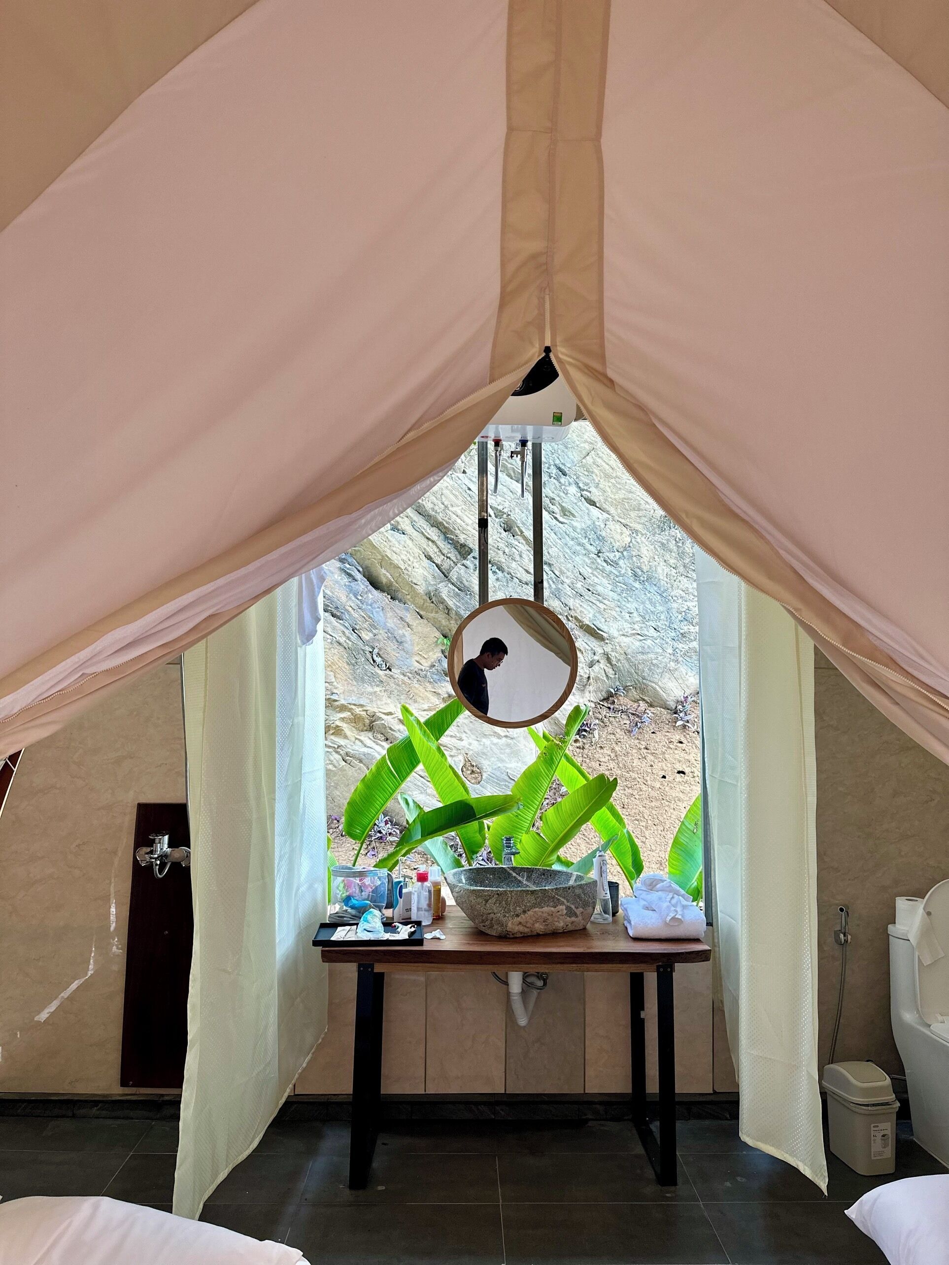 Una habitación con tienda que incluye un espejo grande, una mesa con artículos de aseo personal y vistas a un paisaje rocoso.