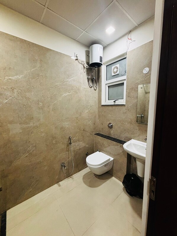 A bathroom with a toilet, sink, and shower area. - Nirvana inn (Prayagraj)