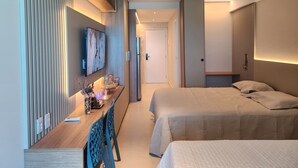 Moderni hotellihuone, jossa on puinen työpöytä, sänky ja seinälle asennettu televisio.