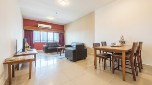 Een moderne woonkamer met een bank, een eettafel met stoelen, een kleine salontafel en een televisie.