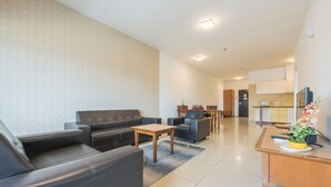 Een moderne woonkamer met een bank, salontafel en stoelen, een keuken met kasten en een eettafel, en een klein kantoor met bureau en stoel.