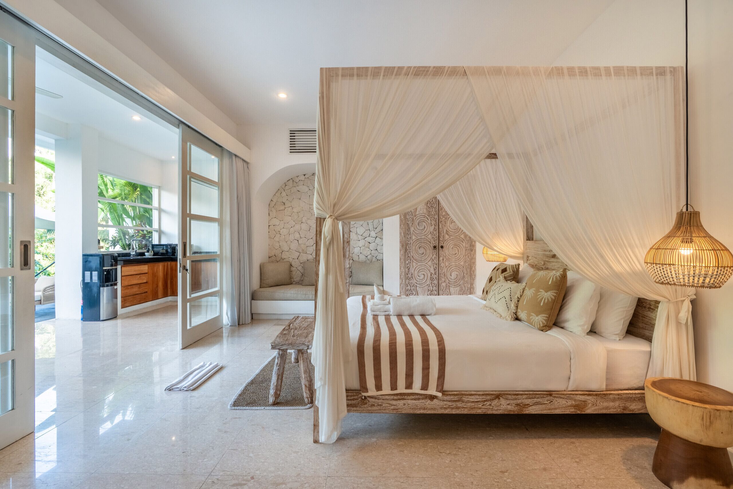 A spacious bedroom with a large bed, a canopy, and a view of the outdoor area.