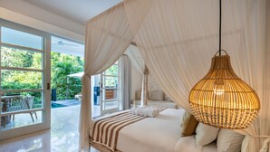 A bedroom with a canopy bed, a hanging light fixture, and a view of the outdoors.
