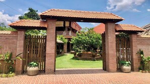 Una entrada de ladrillo con un portón de madera y una estructura de techo con tejas.