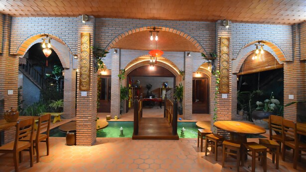 Un restaurante con arcos de ladrillo, mesas de madera y un pasillo central.