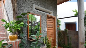 Un patio con un muro de piedra, una puerta de madera y diversas macetas con plantas.