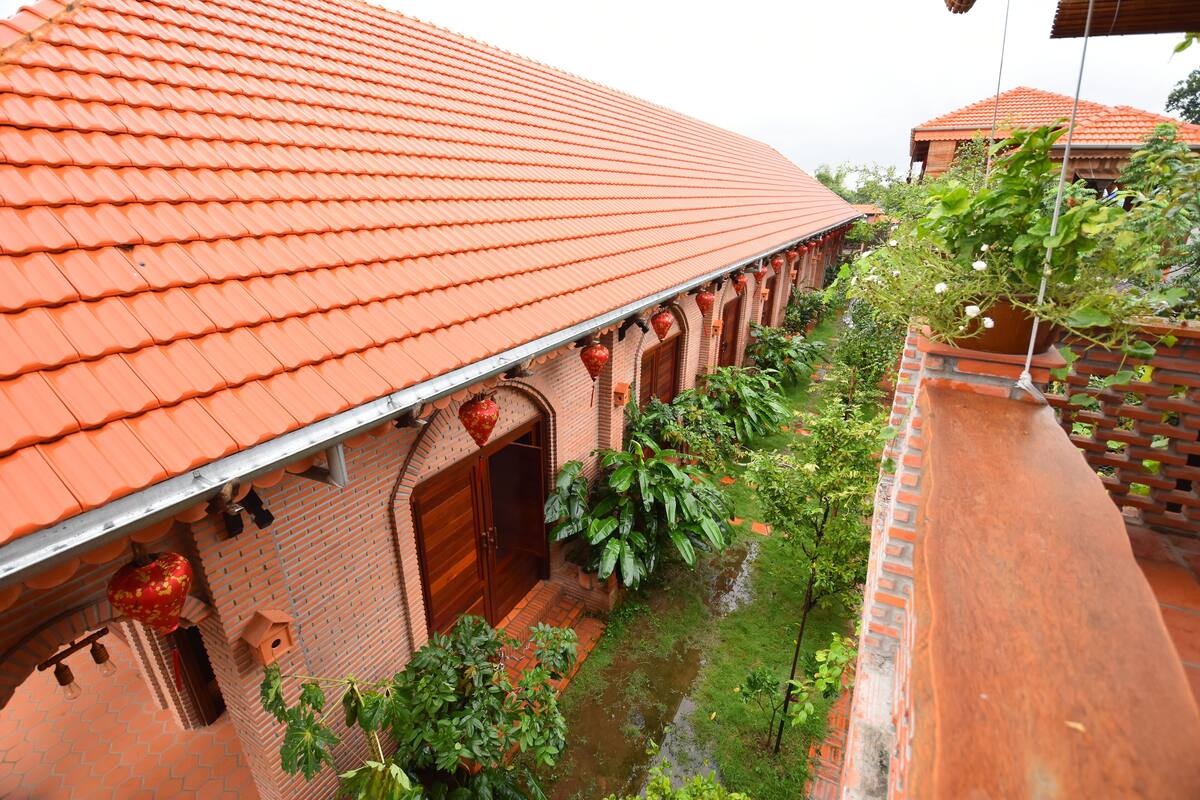 A traditional building with a red tiled roof, brick walls, and a small courtyard with plants and a water feature.