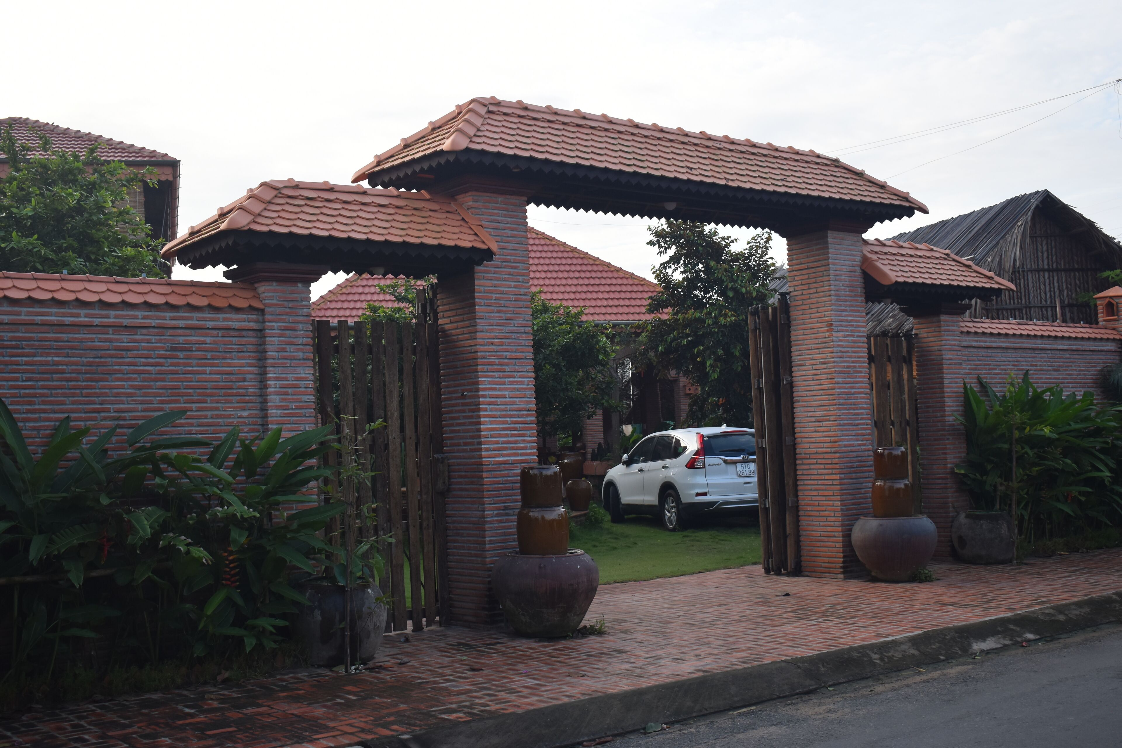A brick building with a tiled roof, a gated entrance, and potted plants.