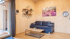 Una sala de estar moderna con piso de madera, un sofá azul, una mesa de centro y un ventanal con cortinas.
