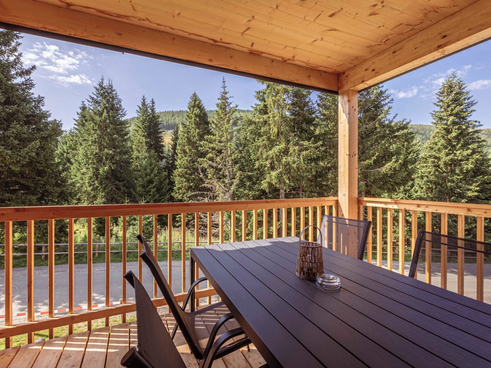 A wooden deck with a table and chairs overlooking a lake and forest.