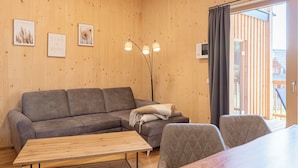 A cozy room with a wooden interior, a sofa, a table, and a floor lamp. - mit 2 Schlafzimmern & Sauna by Interhome (Niederwölz)