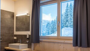 Une salle de bain moderne avec un lavabo, un miroir et une fenêtre avec des rideaux.