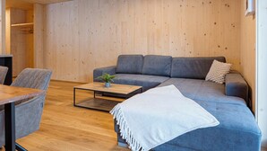 A modern living room with a grey sofa, a small coffee table, and a wooden floor.
