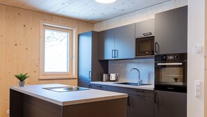 A modern kitchen with a central island, built-in appliances, and a window providing natural light.