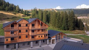 A multi-story wooden building with balconies, set against a mountainous backdrop.
