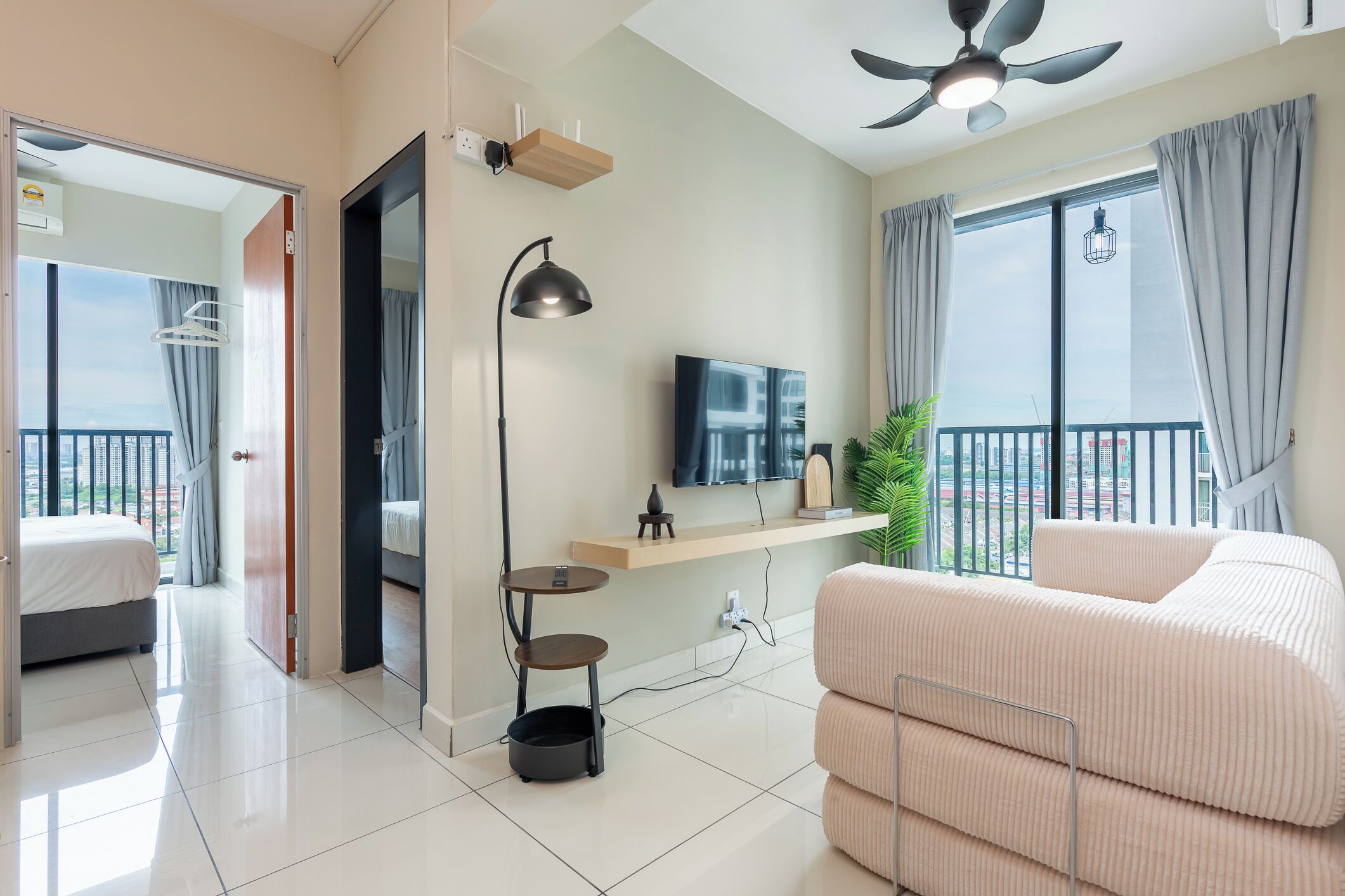 Ein modernes Hotelzimmer mit Balkon, Flachbildfernseher, Deckenventilator und einer Couch.