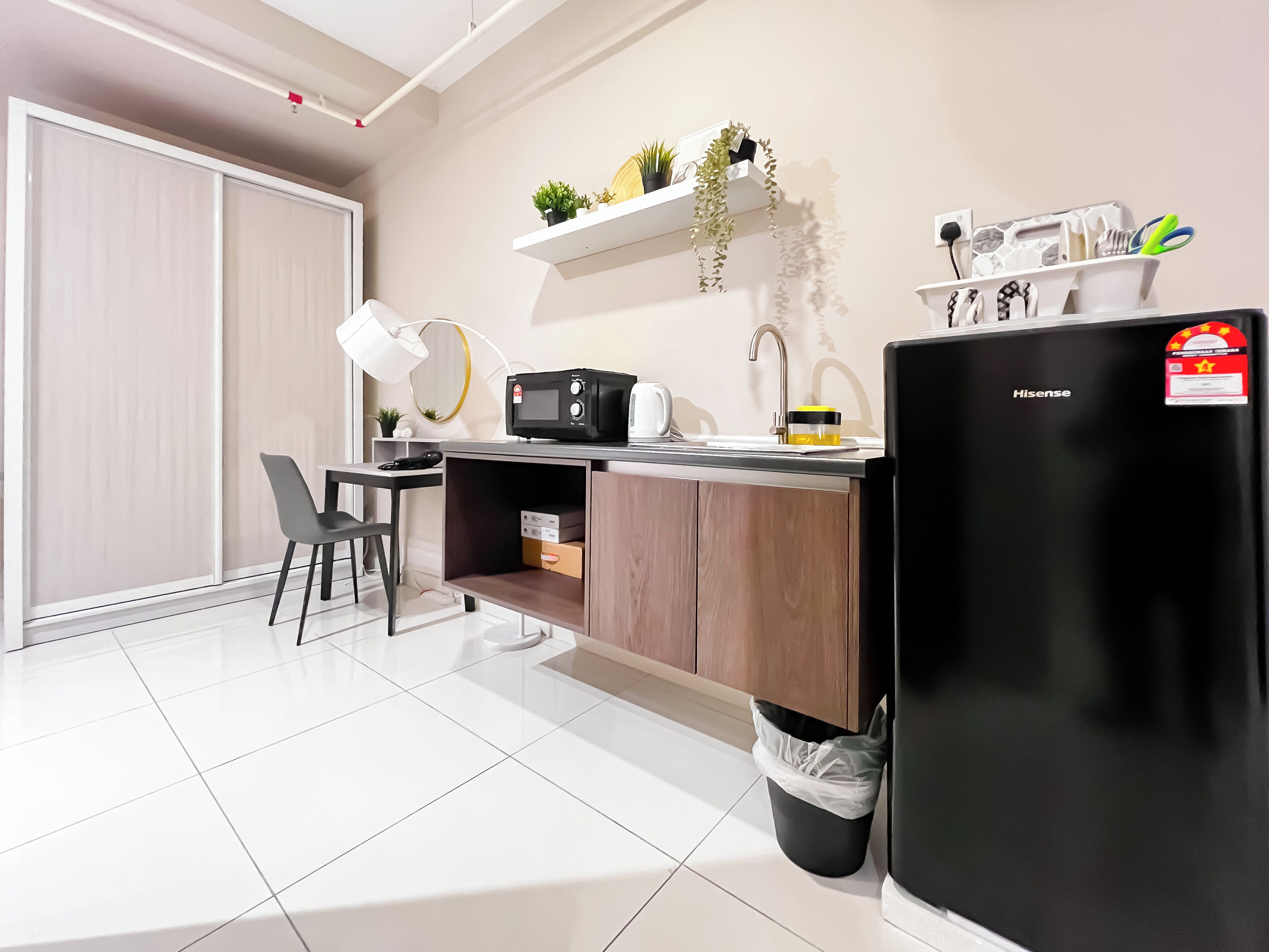 A compact kitchenette with a microwave, sink, and Hisense refrigerator.