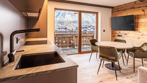 Une cuisine moderne dotée d’un évier encastré et offrant une vue sur les montagnes grâce à une porte-fenêtre coulissante.
