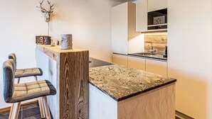 Una cocina moderna con techo de madera, encimera de mármol y decoración rústica.