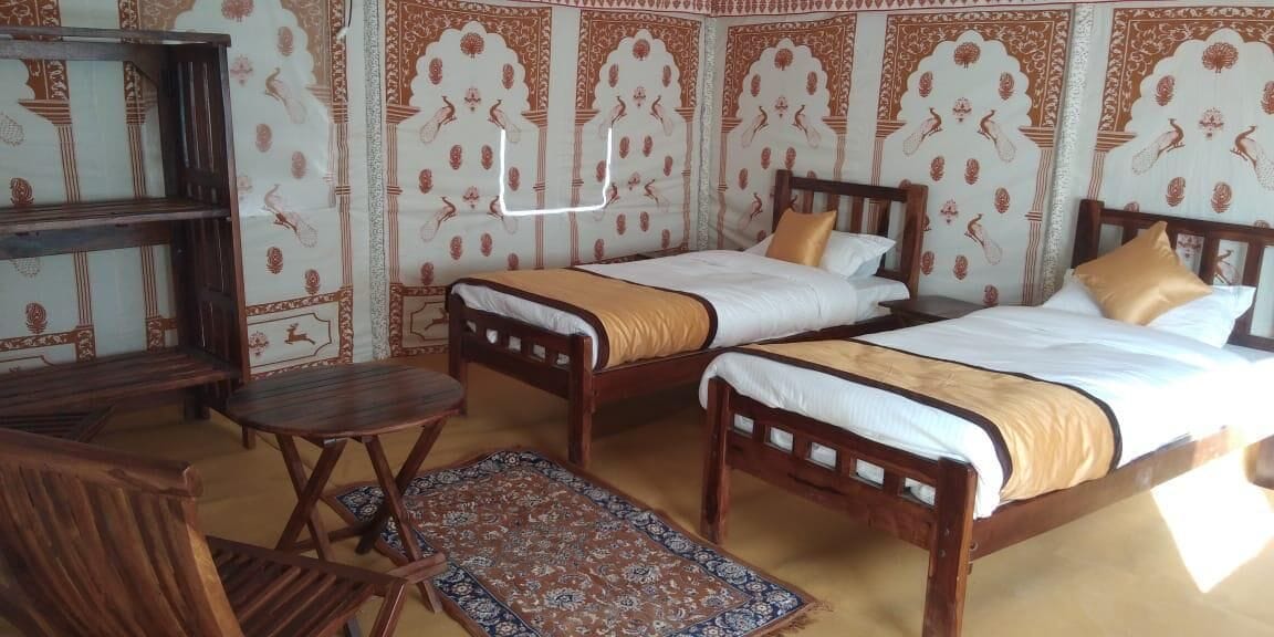 A room with two wooden beds, a wooden chair, and a small table.