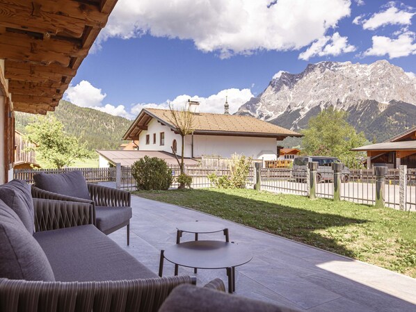 A patio with outdoor furniture, a mountain view, and a traditional chalet-style building. - mit 3 Schlafzimmern für 6 Personen by Interhome (Lermoos)