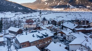 Une ville enneigée, avec des bâtiments traditionnels, une église imposante et une montagne en arrière-plan.