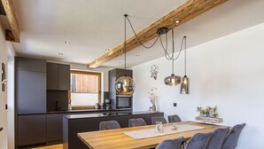 Une cuisine moderne avec un îlot central en bois, des meubles de rangement aux couleurs sombres et un éclairage suspendu.