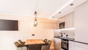 Una cocina moderna con una mesa y sillas de madera, horno empotrado y microondas.
